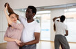 © JackF - African-american man and caucasian woman training pair dance in dancing studio.