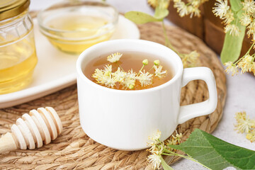 Cup of linden tea and bowl with honey on white table