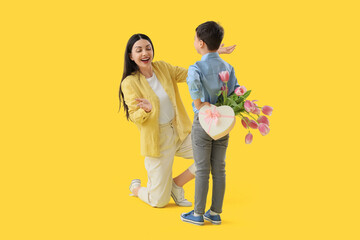 Poster - Mother receiving gifts from her little son on yellow background