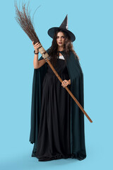 Wall Mural - Young witch with broom on blue background