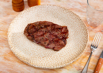 Poster - Appetizing roast piece of veal meat dished up in a plate on the laid restaurant table