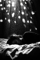 A serene black and white image of a woman peacefully sleeping on a bed, illuminated by soft light filtering through curtains.