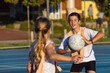© Austockphoto - two children on an outdoor netball court passing the ball
