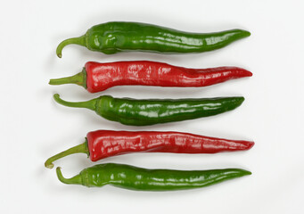 Wall Mural - Close-up of raw hot peppers in a line with three green and two red on white floor, South Korea