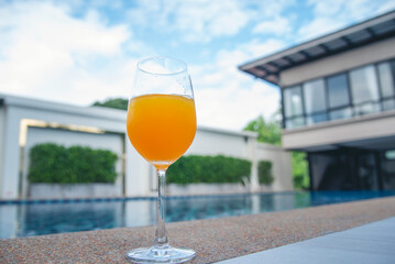 Orange juice cool drinks sweet freshness drinking poolside at blue swimming pool in tourist resort. Orange smoothie juicy healthy mocktail organic cool juice glass. Sweet healthy beverage cool drinks