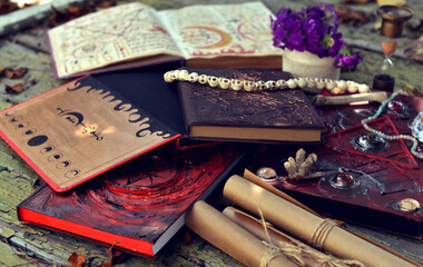 Mystic still life with magic book of spells, old manuscripts and witchy ritual objects on old table. Occult, esoteric, wicca and divination concept. No foreign language, all symbols are fictional