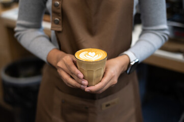 Wall Mural - a person holding a cup of latte with a heart on it.