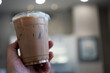 © Dontree - Iced mocha coffee in take away glas on hand and blurred background