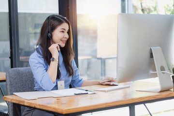 Young asian businesswoman with headset using desktop computer for customer support and online working in office, Call center helping for customers online concept.