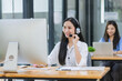 © SOMKID - Young asian businesswoman with headset using desktop computer for customer support and online working in office, Call center helping for customers online concept.