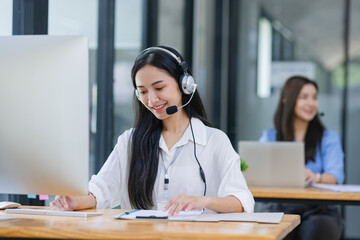 Young asian businesswoman with headset using desktop computer for customer support and online working in office, Call center helping for customers online concept.