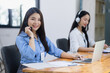 © SOMKID - Young asian businesswoman with headset using desktop computer for customer support and online working in office, Call center helping for customers online concept.