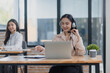 © SOMKID - Young asian businesswoman with headset using desktop computer for customer support and online working in office, Call center helping for customers online concept.