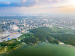 Big lake with green shores in bright sun light and city on horizon, aerial landscape. Recreation concept. Aerial view