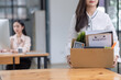 © SOMKID - Young asian woman employee with a storage box for the equipment after resigning and stressed from work.