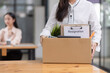 © SOMKID - Young asian woman employee with a storage box for the equipment after resigning and stressed from work.