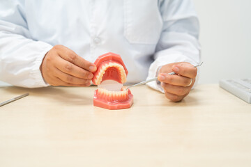  A female doctor sits at a table in a hospital, discussing dental issues like wisdom teeth, cavities, dentures,missing teeth, and cracked teeth, explaining the causes and treatment of dental caries.