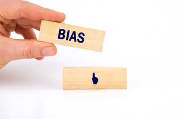 Wall Mural - Concept of facts and biases. A word BIAS written laid out by a man's hand with wooden blocks on a white background