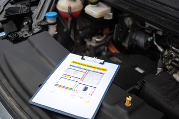 Wall Mural - a multi-point car maintenance and inspection checklist paper on clipboard, that placed at car front 