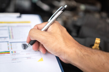 Wall Mural - close-up at a mechanic foreman's hand is checking on multi-point car service guideline checklist for