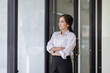 © David - Happy confident asian professional business woman standing at work in office arms crossed looking away, asian businesswoman leader executive thinking of future success.