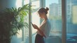 © zen - A woman standing by a large window with natural light pouring in, using her smartphone with a gentle smile, her surroundings hinting at a modern, minimalist interior.