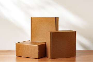 Three Cardboard Boxes Stacked on a Wooden Surface in a Room With Natural Light