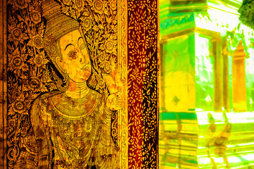 Canvas Print - Thai style paintings on a door with golden pagoda background at a temple in Chiang Mai Province