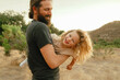 © Cavan Images - dad with beard and pony tail swings around child in mountains