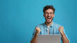 © Paradoxx - A happy smilling man with glasses and a laptop celebrating his success. Generative Ai