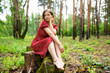© Westend61 - Woman in red dress sitting on tree stump at forest