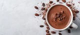 Top down view of a homemade hot chocolate drink adorned with chocolate cocoa and cocoa beans on a white textured backdrop ideal for adding text or images. with copyspace image
