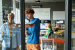 © Mediaphotos - Two young people writing formulas on glass wall and collaborating on IT project together during class in school or college, copy space