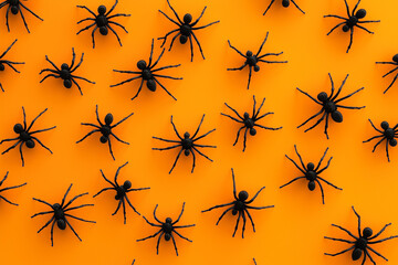 A pattern of black spiders on an orange background. Halloween background. 