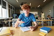 © Mediaphotos - POV of red haired young man gesturing and looking at camera while talking to video chat in school