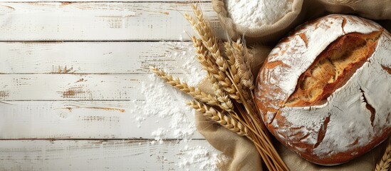 Poster - Top view of a loaf of bread with wheat ears and a bag of flour on a white wooden surface creating a baking bread background with copy space image