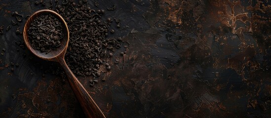 Poster - Close up of black tea leaves in a wooden spoon on a dark background with copy space image
