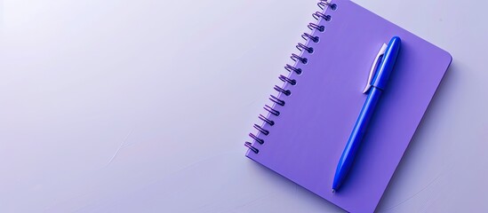 Wall Mural - Purple notebook and blue pen viewed from above on a white background making it suitable for school or office themed wallpapers with a flat lay composition and ample copy space image