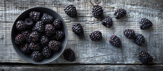 Aufkleber - Black raspberries arranged in a bowl on the left with a gray wooden table background on the right offering ample copy space image