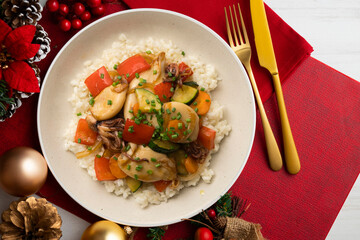 Wok-fried calmares with vegetables over white rice. Food on a table with Christmas decorations.