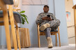 © Wavebreak Media - Sitting in chair, soldier with prosthetic leg using smartphone in waiting room