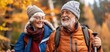 © Anna - Cheerful elderly couple hiking in autumn forest.