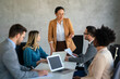 © NDABCREATIVITY - Multicultural professional businesspeople working together on research plan in boardroom.