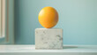 © João Macedo - Yellow sphere balancing on a stone cube on a table