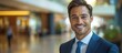 © Sunshine - Confident Businessman Smiling in Modern Office Building with Blurred Background