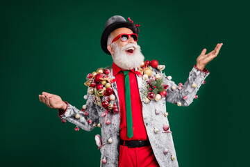 Sticker - Photo of cool pensioner santa claus male look empty space catch dressed balls baubles on jacket hat sunglass isolated on green background