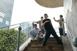 © DragonImages - Group of friends posing on city stairway with tall buildings in background and greenery nearby, capturing candid moments on an urban adventure