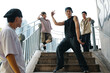 © DragonImages - Group of young men dancing on stairs in urban setting, wearing casual streetwear. Capturing moment of dynamic energy and individual expression