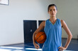 © WavebreakMediaMicro - Holding basketball, female basketball player standing confidently on indoor court, copy space