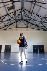 Wall Mural - Holding basketball, athlete standing on indoor court, preparing for practice, copy space